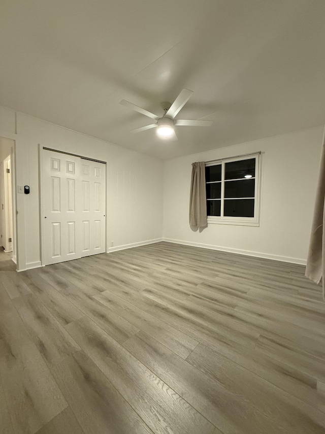 unfurnished bedroom with a ceiling fan, wood finished floors, baseboards, and a closet