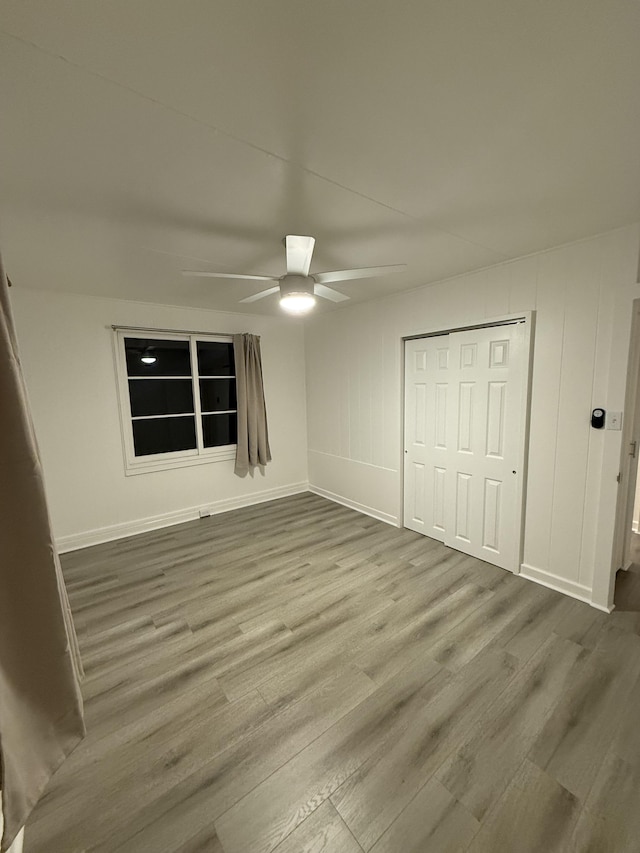 unfurnished bedroom with a ceiling fan, wood finished floors, a closet, and baseboards