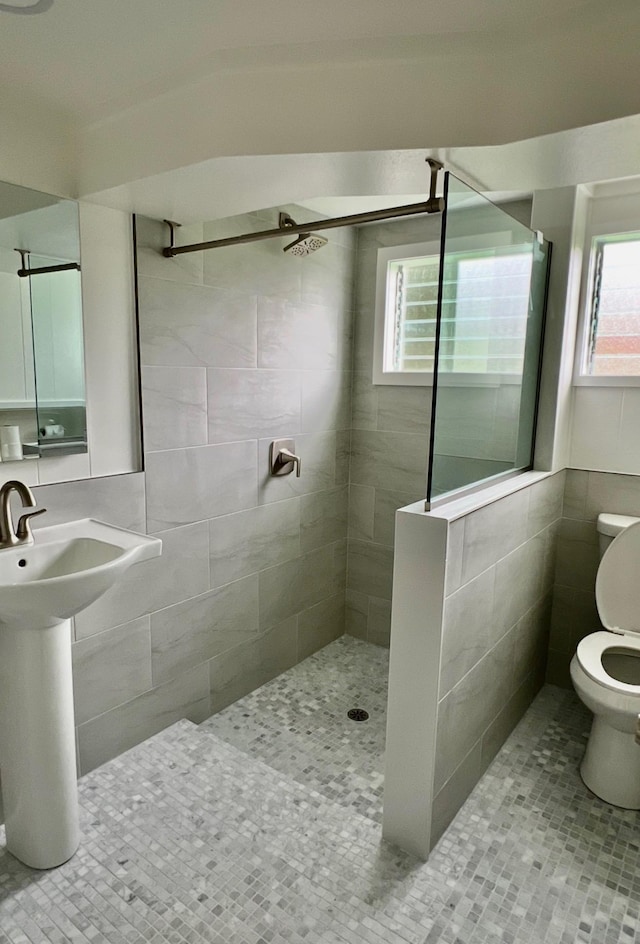 full bathroom with tile patterned floors, toilet, a walk in shower, a sink, and tile walls