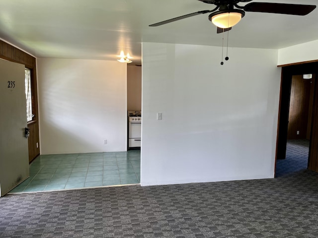 spare room featuring ceiling fan, carpet flooring, and tile patterned floors