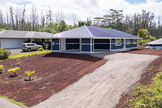 ranch-style home with driveway, metal roof, and a carport