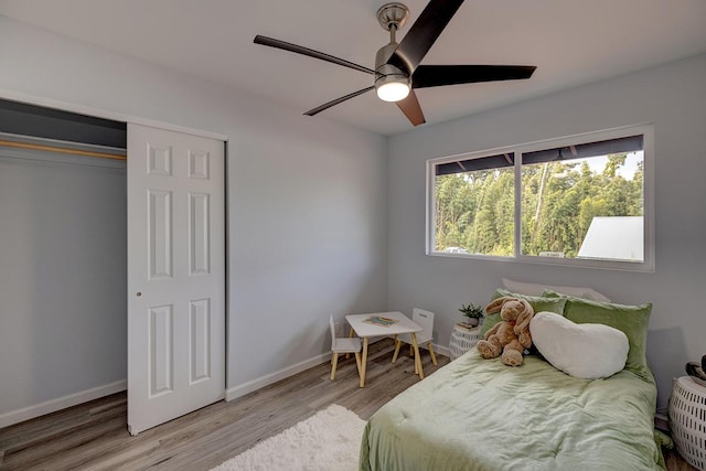 bedroom with a closet, ceiling fan, baseboards, and wood finished floors