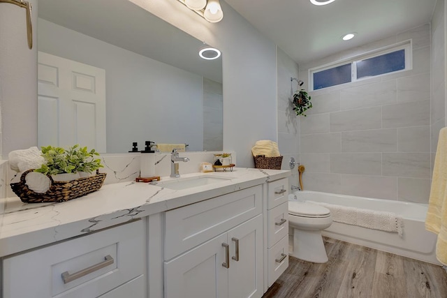 bathroom featuring toilet, vanity, wood finished floors, and bathing tub / shower combination