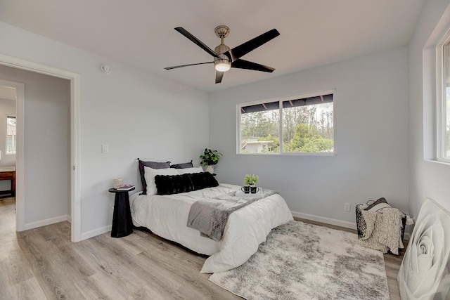 bedroom with a ceiling fan, baseboards, and wood finished floors