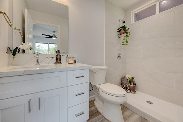 full bathroom with toilet, wood finished floors, tiled shower, and vanity