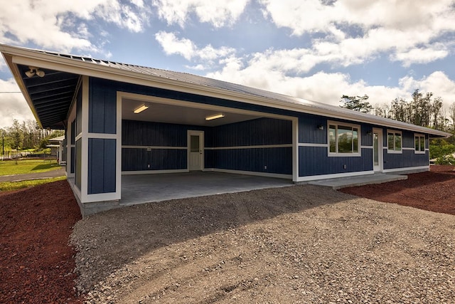 exterior space featuring dirt driveway, metal roof, and a garage