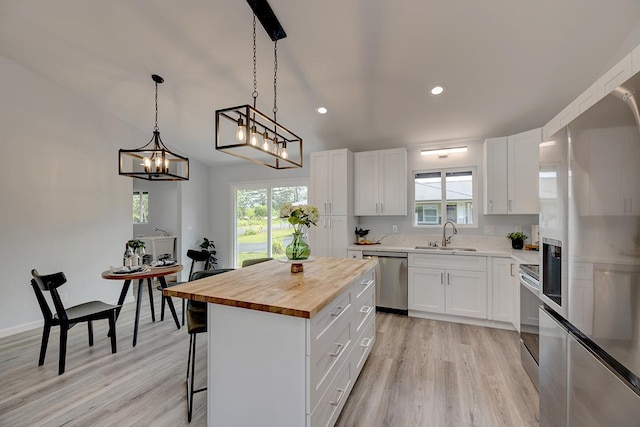 kitchen featuring wooden counters, appliances with stainless steel finishes, a sink, and white cabinets