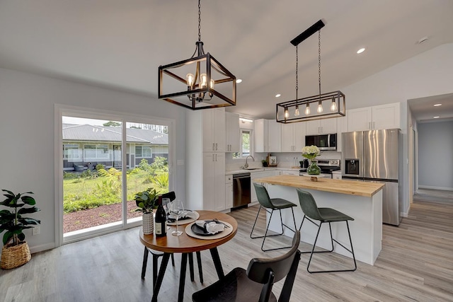 kitchen featuring a sink, white cabinets, wooden counters, appliances with stainless steel finishes, and a center island