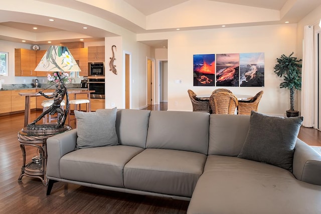 living room featuring a tray ceiling, recessed lighting, wood finished floors, and vaulted ceiling