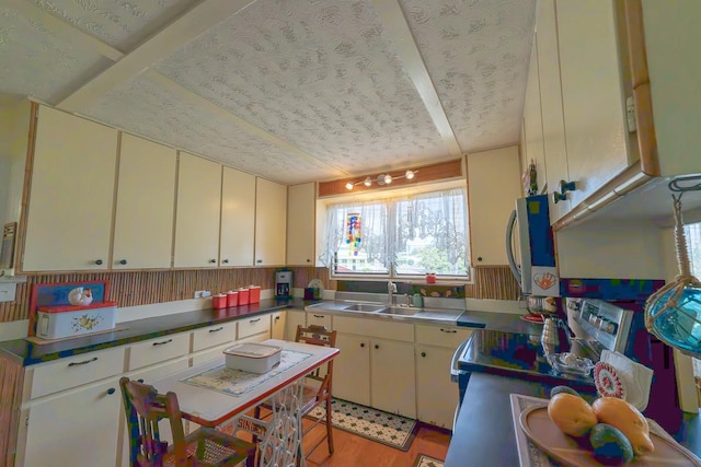 kitchen featuring stainless steel appliances, cream cabinets, a sink, and light wood-style floors