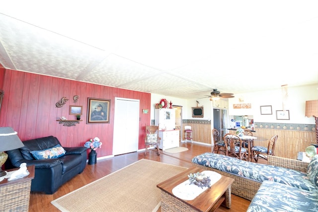 living area featuring wood walls, a ceiling fan, and wood finished floors