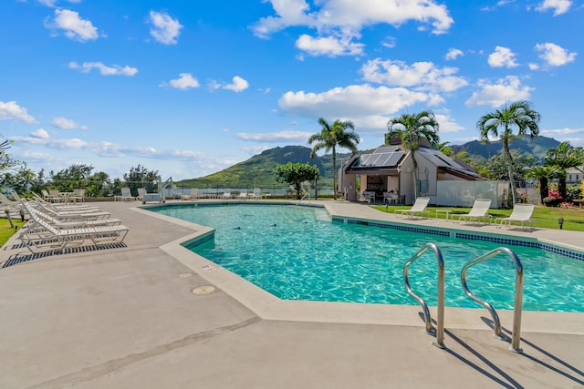 community pool with fence, a patio area, and a mountain view