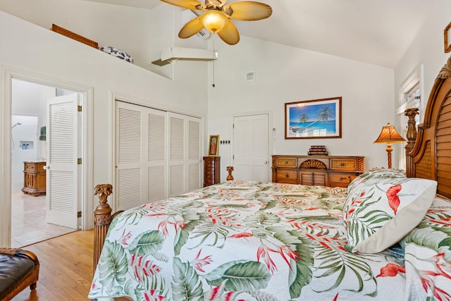 bedroom featuring ceiling fan, visible vents, light wood-style floors, vaulted ceiling, and a closet