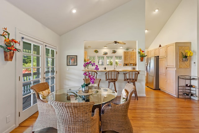 dining room featuring light wood-style floors, ceiling fan, high vaulted ceiling, and french doors