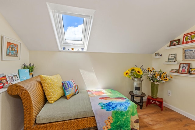 bedroom with lofted ceiling with skylight, wood finished floors, and baseboards