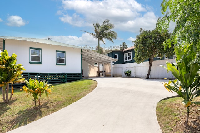 view of front of property with concrete driveway, an attached carport, a front yard, and fence