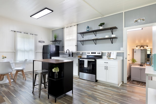 kitchen with freestanding refrigerator, stainless steel electric range, and open shelves