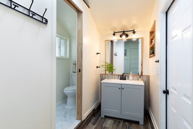 bathroom with toilet, baseboards, wood finished floors, and vanity