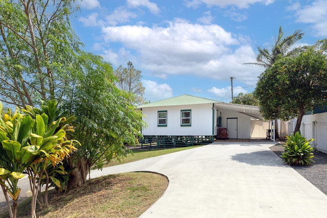 view of front of home featuring driveway, an attached carport, and fence