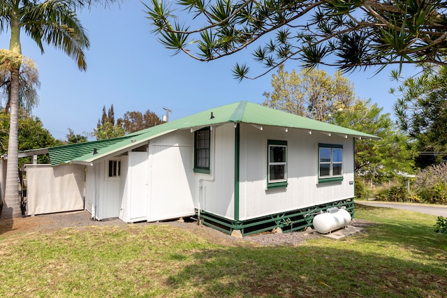 view of side of home featuring metal roof and a yard