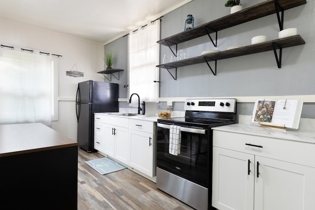 kitchen featuring freestanding refrigerator, stainless steel electric range, light countertops, open shelves, and a sink