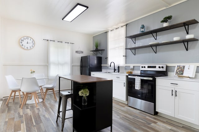 kitchen featuring white cabinets, light wood-style flooring, freestanding refrigerator, stainless steel electric range, and open shelves