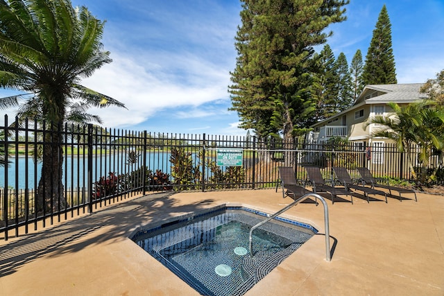 view of swimming pool featuring a water view, fence, and a community hot tub