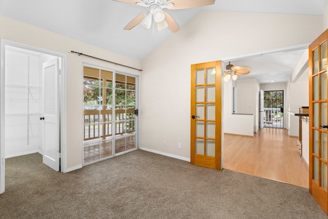 carpeted spare room with vaulted ceiling, french doors, a ceiling fan, and baseboards