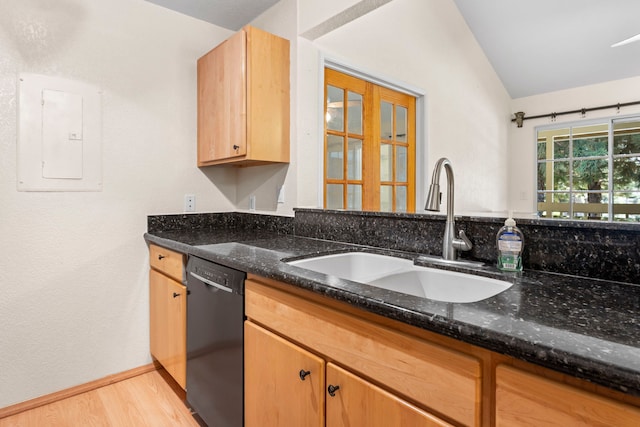 kitchen with black dishwasher, a sink, dark stone countertops, light wood-type flooring, and electric panel