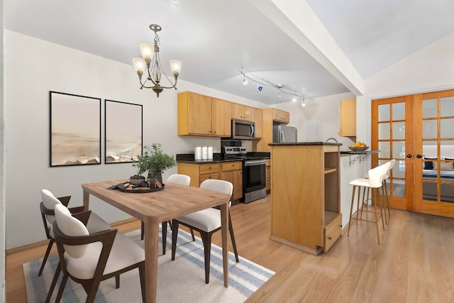 kitchen featuring a notable chandelier, stainless steel appliances, dark countertops, light wood-style flooring, and light brown cabinetry