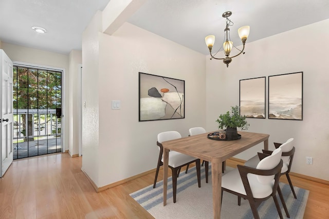 dining area with light wood-type flooring, baseboards, and a notable chandelier