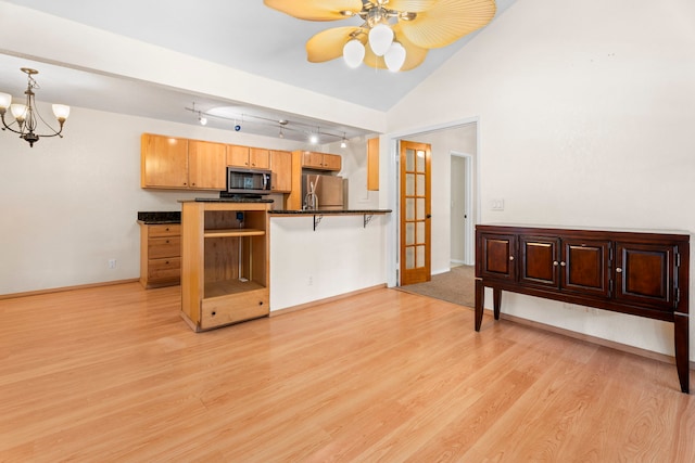 kitchen with lofted ceiling, stainless steel appliances, baseboards, light wood-type flooring, and dark countertops