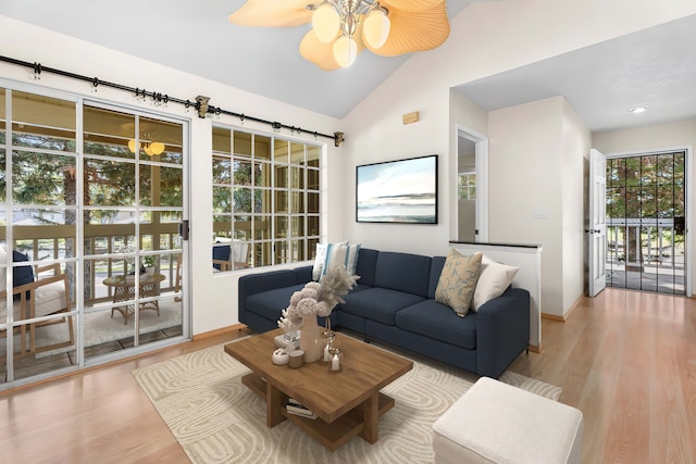 living area featuring lofted ceiling, ceiling fan, wood finished floors, and baseboards