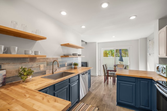 kitchen with open shelves, a sink, appliances with stainless steel finishes, blue cabinets, and butcher block counters