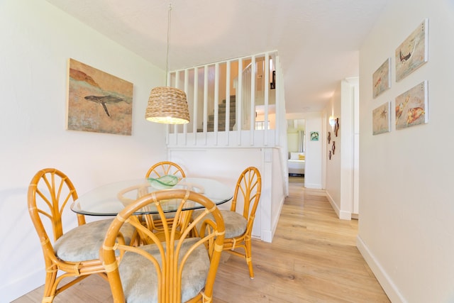 dining room with light wood-style floors, baseboards, and stairs