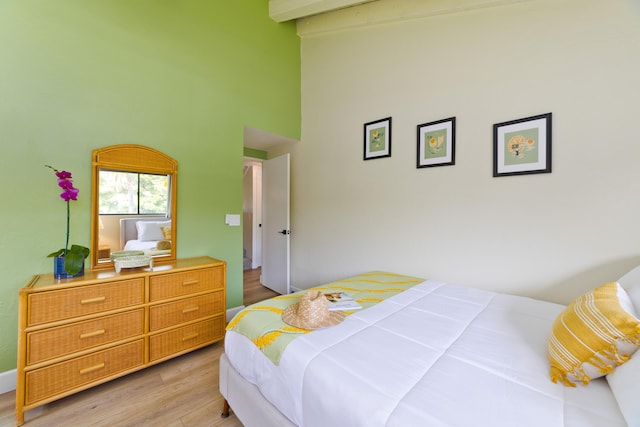 bedroom featuring light wood-type flooring, high vaulted ceiling, and beamed ceiling