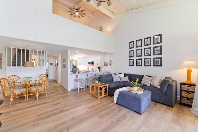 living area with beam ceiling, light wood-style floors, ceiling fan, wooden ceiling, and baseboards