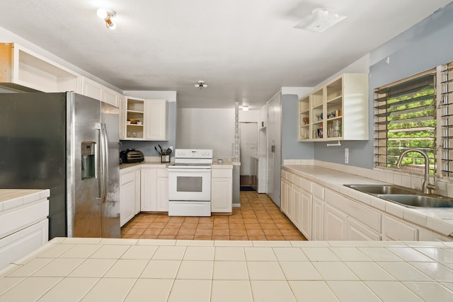 kitchen with open shelves, stainless steel fridge, white electric range, a sink, and tile counters