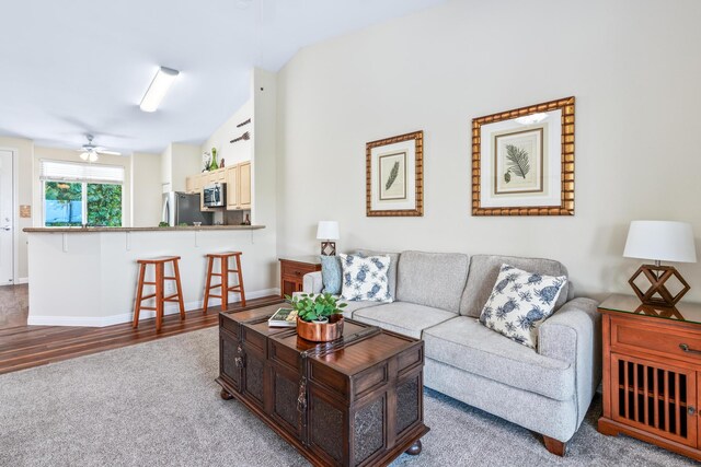 living room featuring baseboards, lofted ceiling, wood finished floors, and a ceiling fan