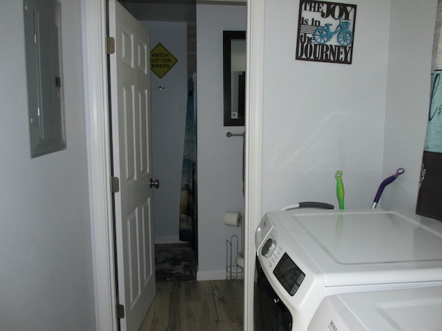 washroom featuring washing machine and dryer, laundry area, electric panel, and wood finished floors