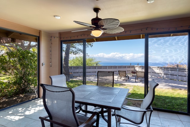 sunroom / solarium featuring outdoor dining space, a ceiling fan, and a water view