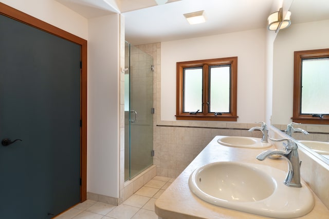 full bath featuring tile walls, a stall shower, tile patterned flooring, and a sink