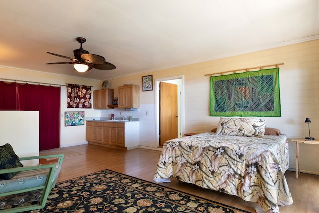 bedroom with light wood-type flooring, ceiling fan, and crown molding