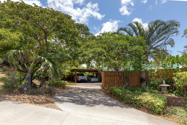 view of home's community with driveway, a carport, and fence