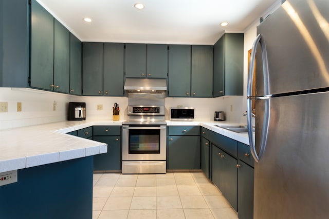 kitchen with recessed lighting, a sink, under cabinet range hood, light tile patterned flooring, and appliances with stainless steel finishes