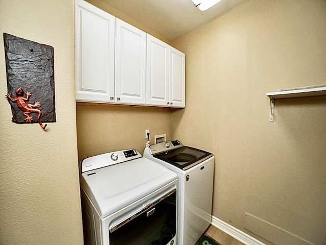 laundry area with cabinet space, washer and dryer, baseboards, and wood finished floors