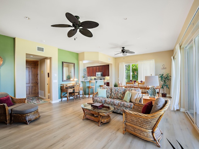 living room with visible vents, baseboards, light wood-style flooring, and a ceiling fan