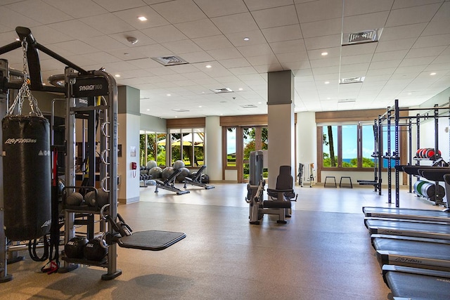 workout area featuring a paneled ceiling, visible vents, and plenty of natural light