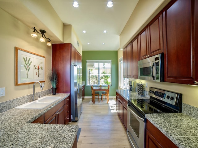 kitchen with dark brown cabinets, light wood-type flooring, recessed lighting, stainless steel appliances, and a sink