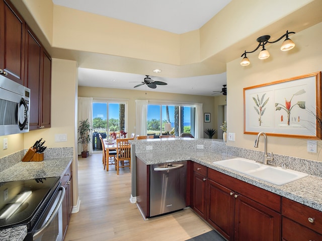 kitchen with ceiling fan, light wood-style flooring, a peninsula, stainless steel appliances, and a sink